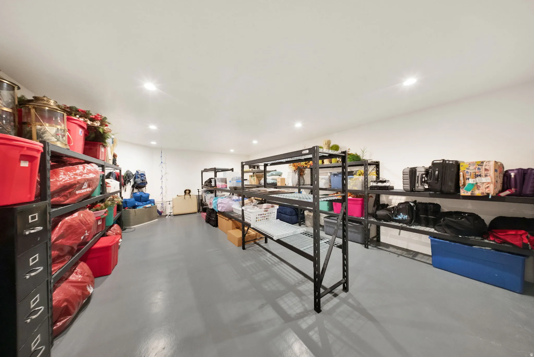 Spacious storage area featuring a smooth grey floor, recessed lighting, and extensive wall-mounted shelving for organization
