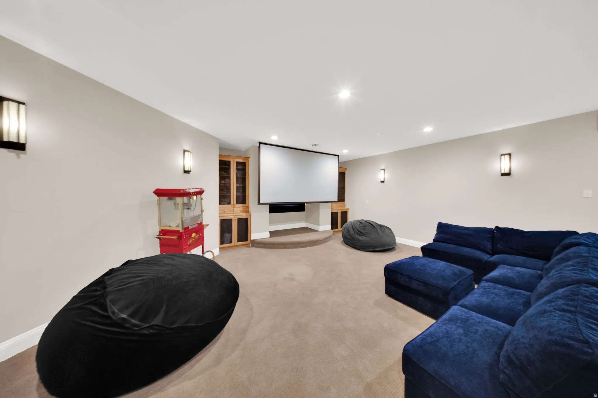 Dedicated media room featuring a large projection screen, recessed lighting, and wall sconces