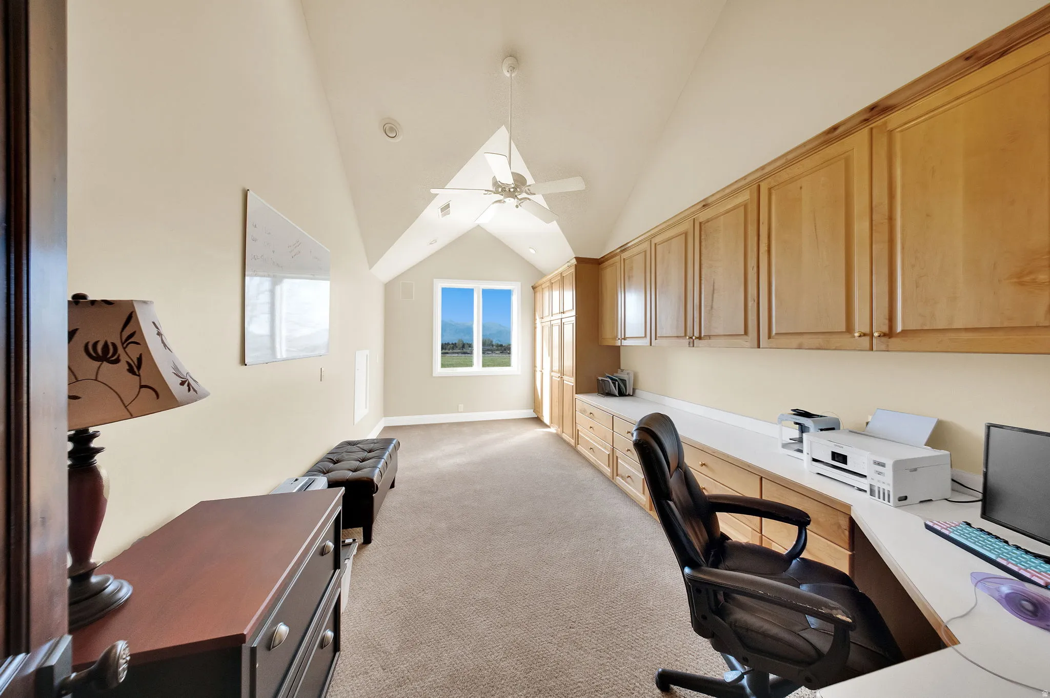 Spacious room featuring vaulted ceilings, a ceiling fan, and ample built-in cabinetry with a dedicated desk area