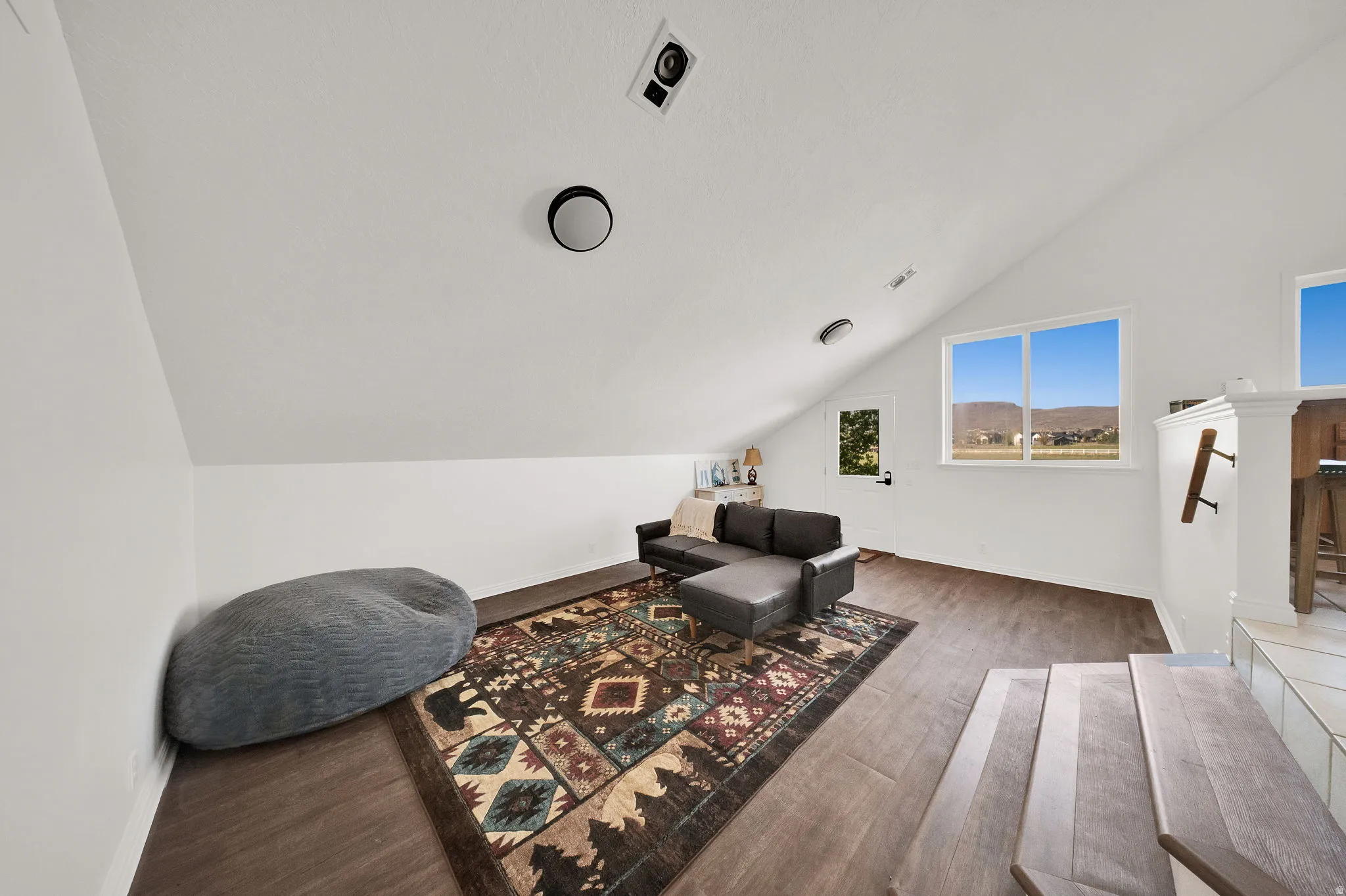 Finished loft space featuring wood-finish flooring, white vaulted ceilings, recessed lighting, and multiple windows