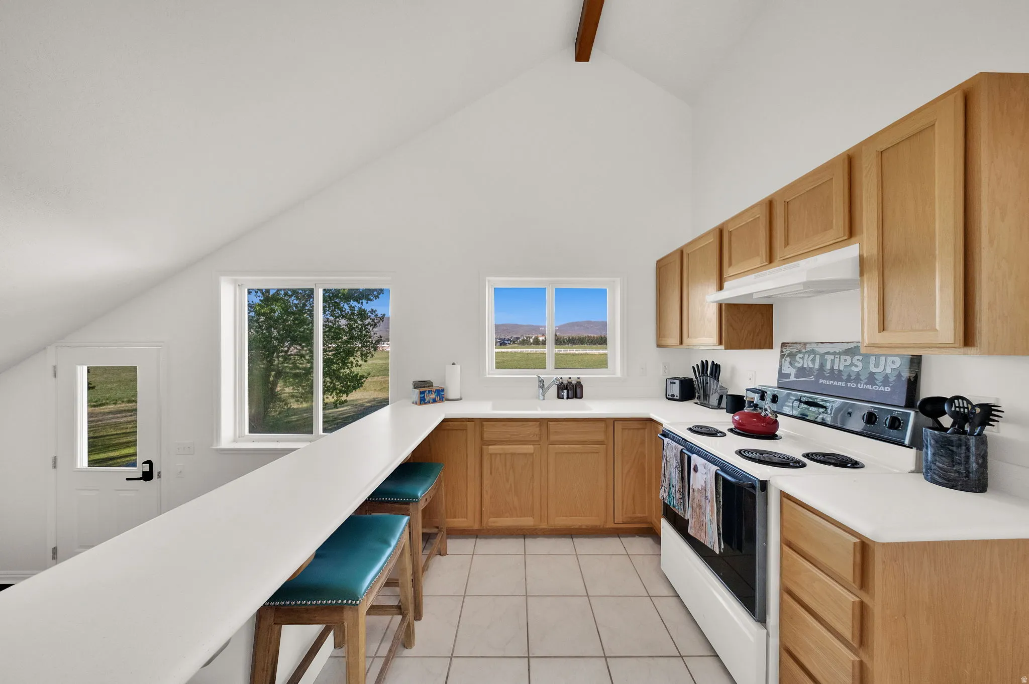Kitchen featuring natural wood cabinetry, white countertops, a built-in electric range, and tile flooring