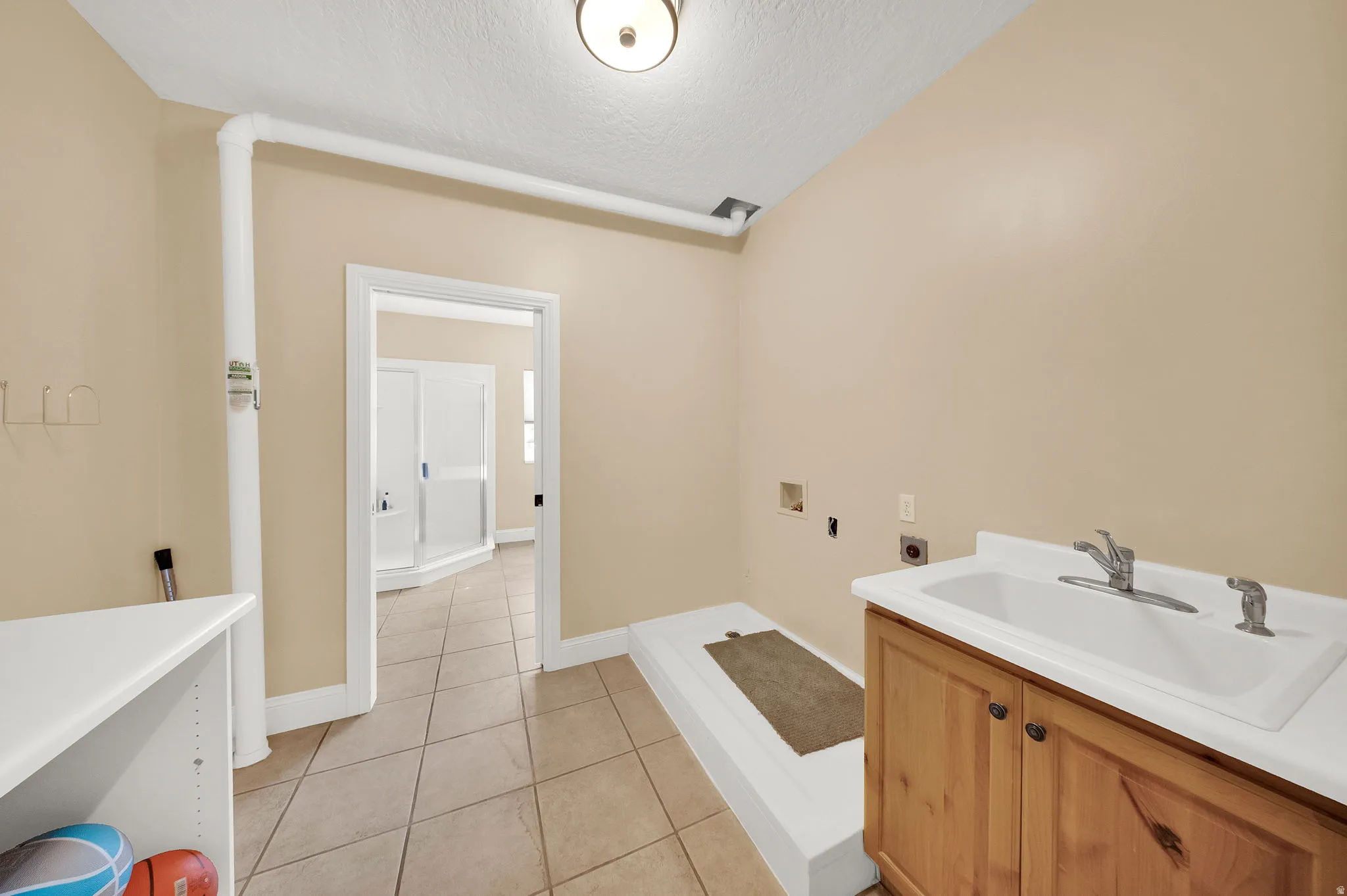 Utility room featuring a built-in sink with cabinetry, tile flooring, and light-toned walls