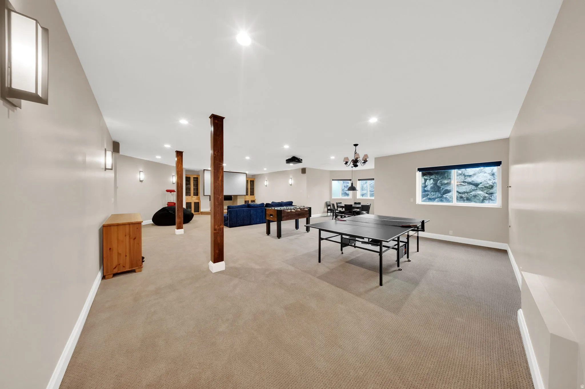 Expansive carpeted room featuring recessed lighting and multiple wall sconces