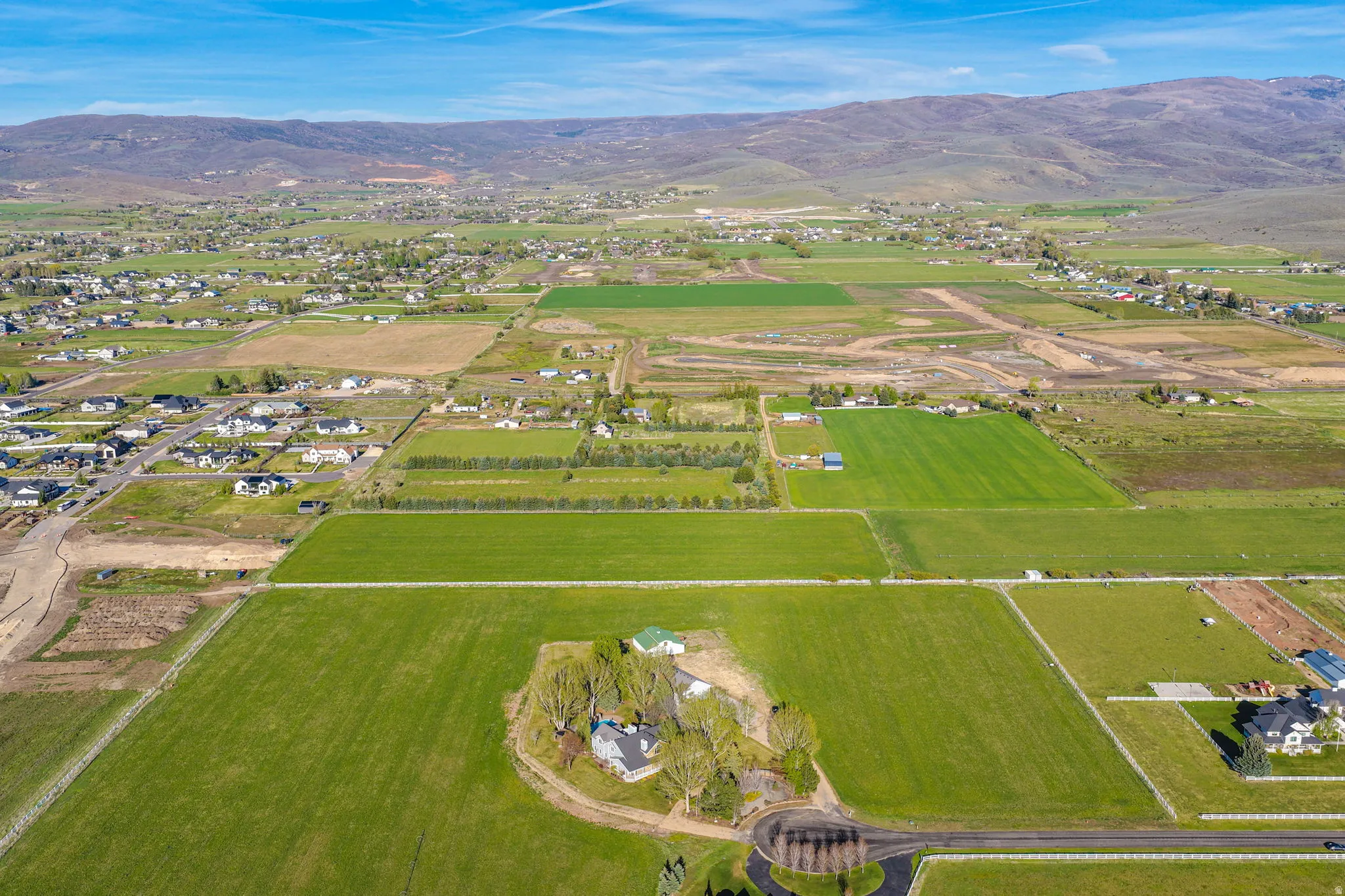 Expansive agricultural land featuring a single-family residence, mature trees, and mountainous terrain
