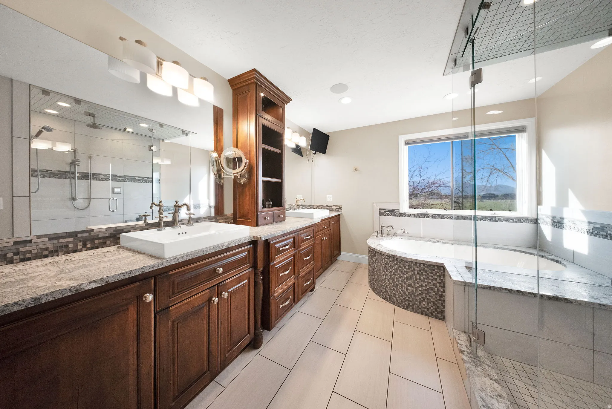 Primary bathroom featuring dual wood-finish vanity with vessel sinks, granite countertops, and full-width mirror