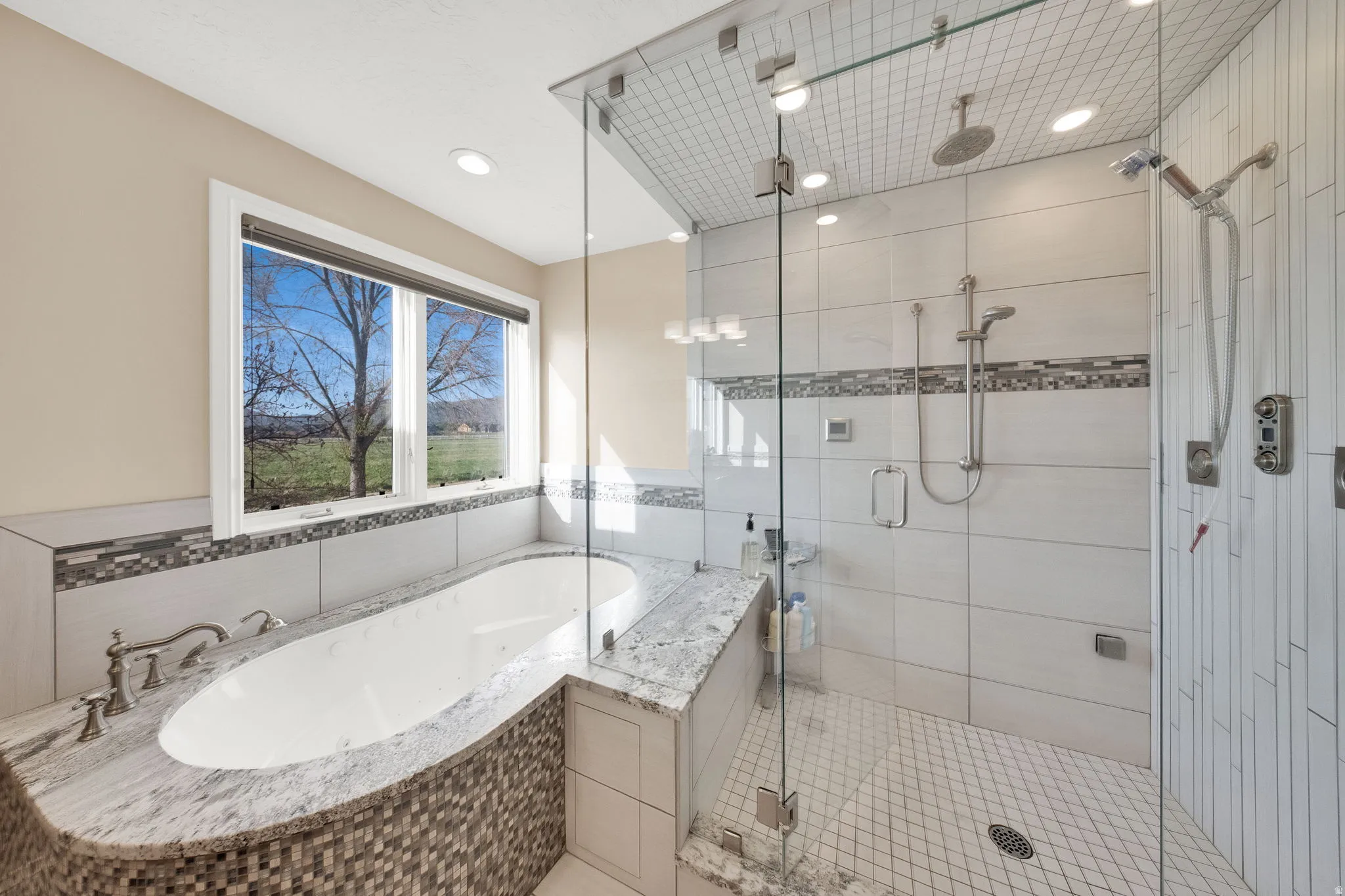 Primary Bathroom featuring a built-in soaking tub with a stone-finish deck and mosaic tile surround