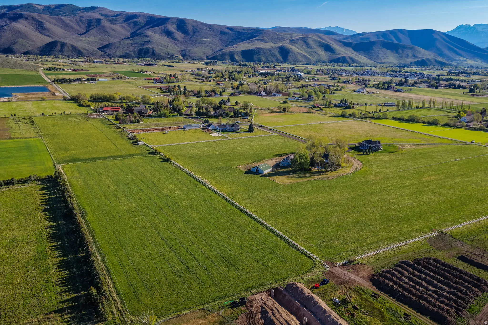 Expansive green fields featuring multiple residential structures and distant mountain ranges