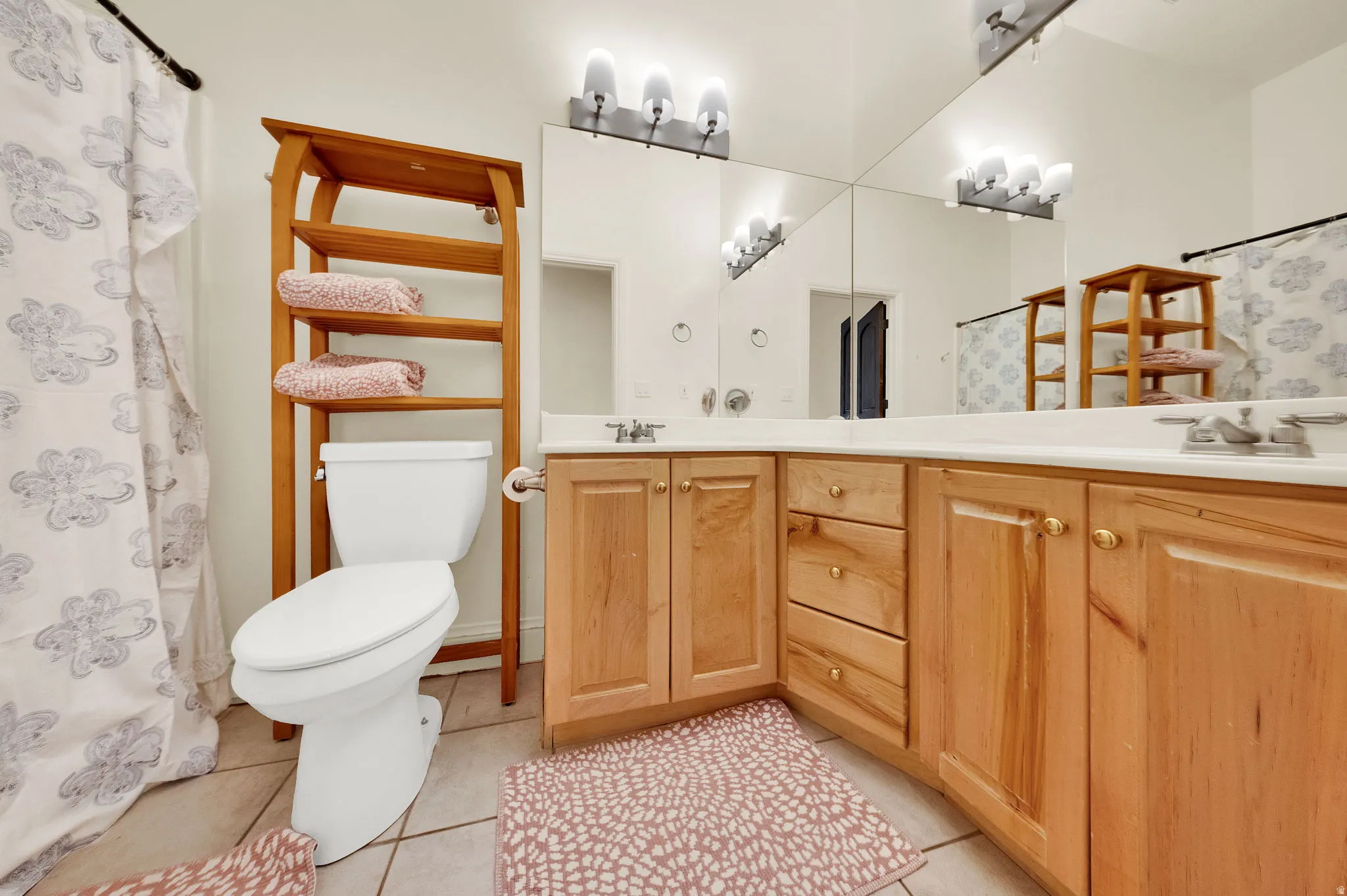 Bathroom featuring a dual vanity with light-tone wood cabinetry, white countertops, and full-wall mirrors