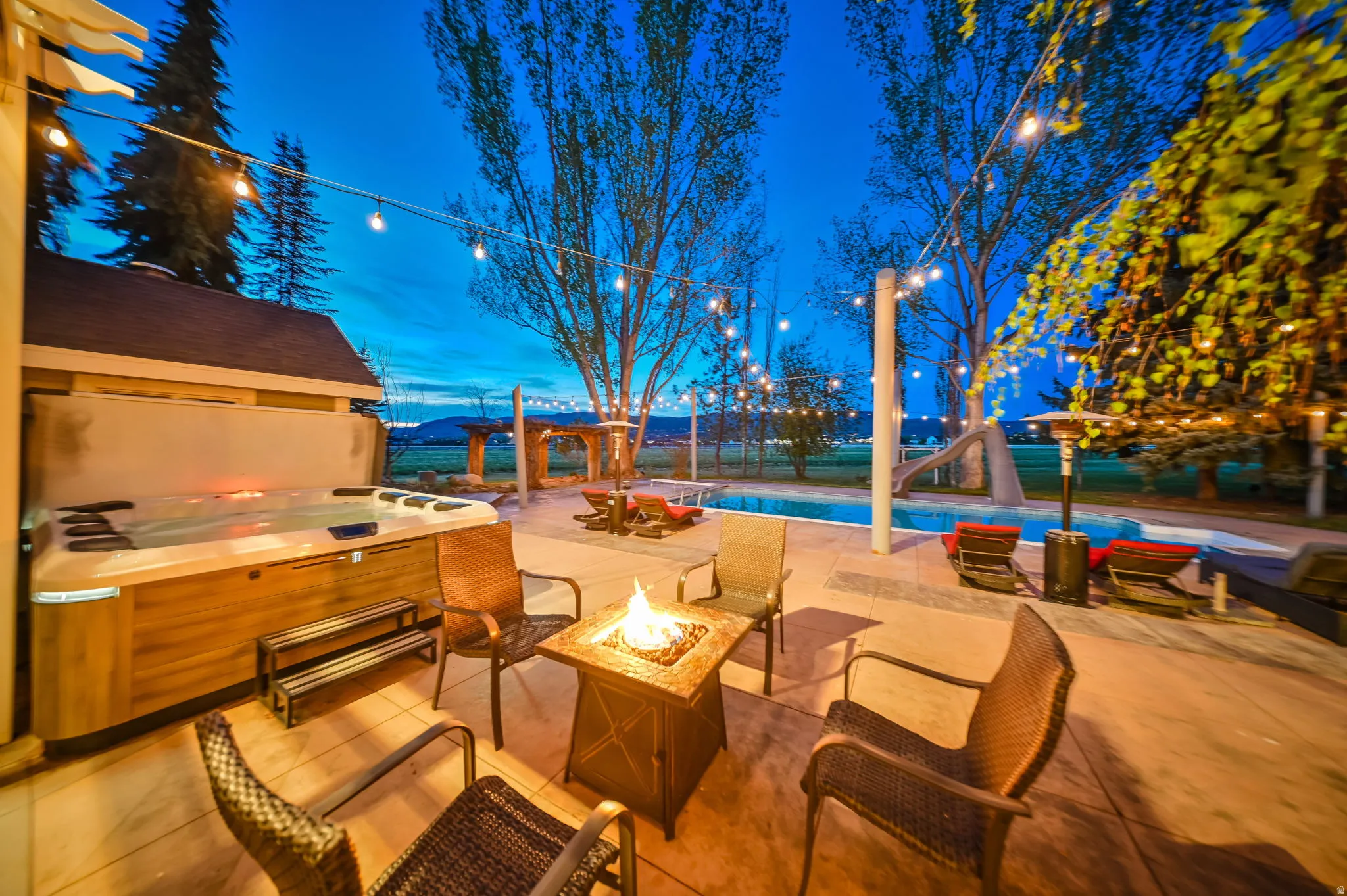 Expansive patio featuring a built-in hot tub, in-ground swimming pool, and string lighting