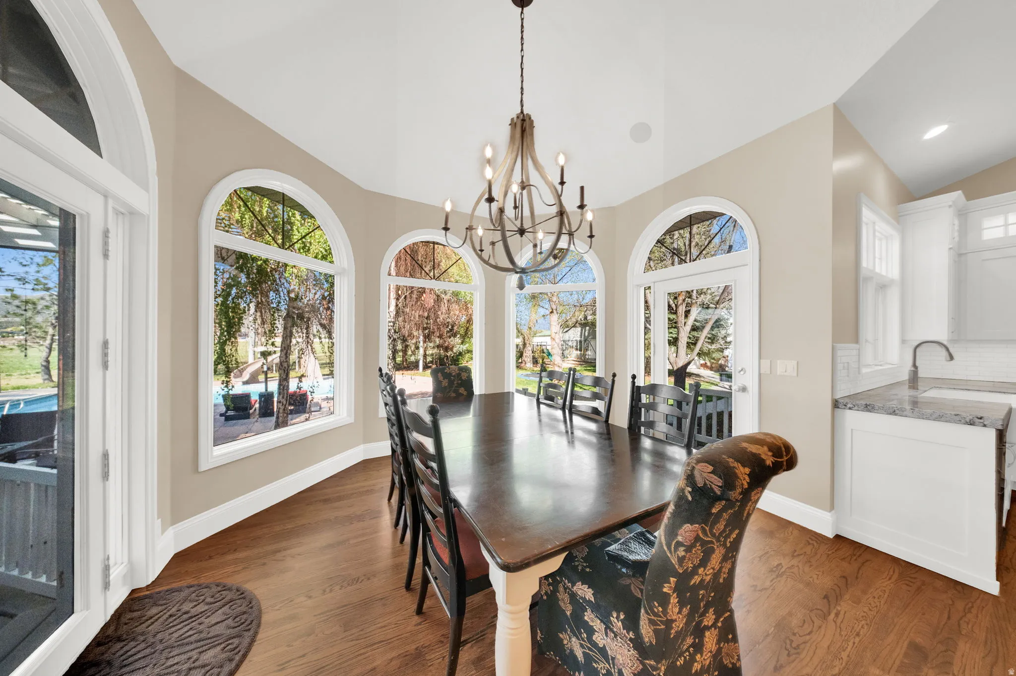 Dining area with vaulted ceilings, hardwood flooring, and multiple arched windows