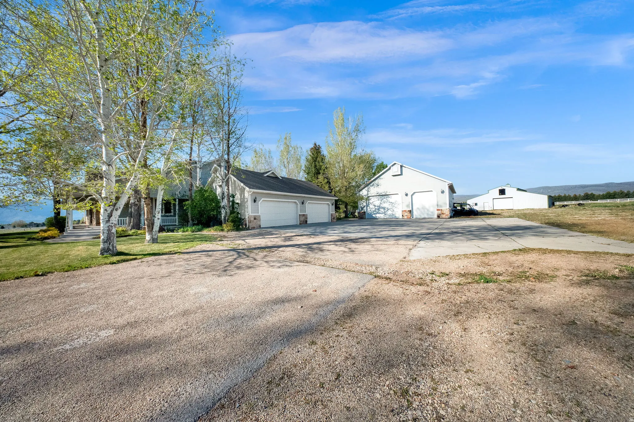 Spacious property featuring a main residence with attached two-car garage, a detached multi-car garage, and a large barn
