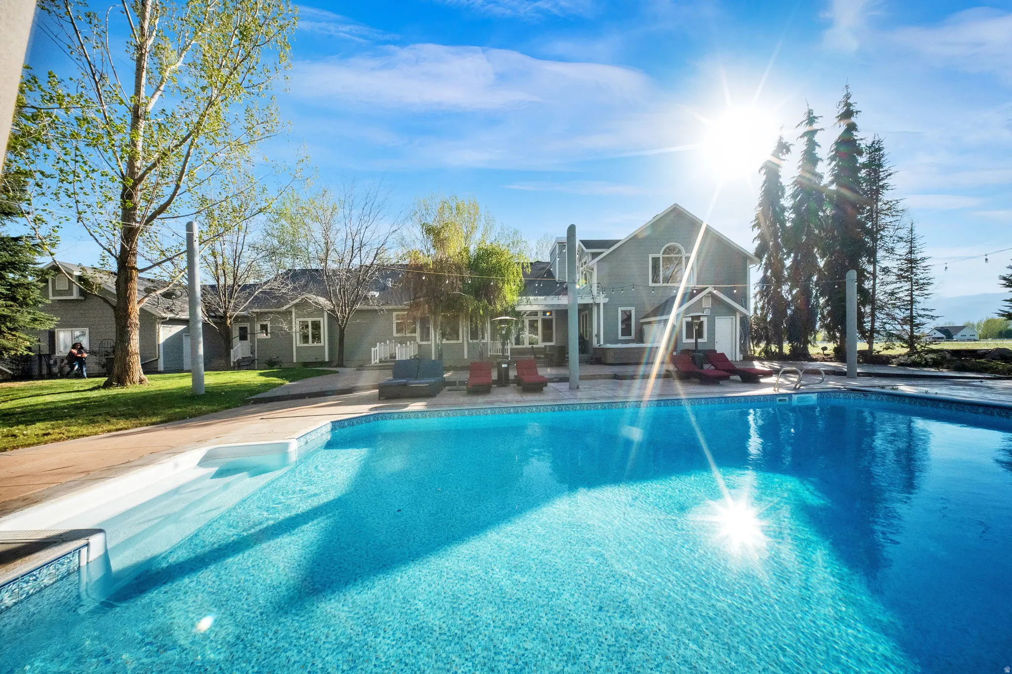 Expansive outdoor swimming pool with integrated steps, surrounded by a paved patio