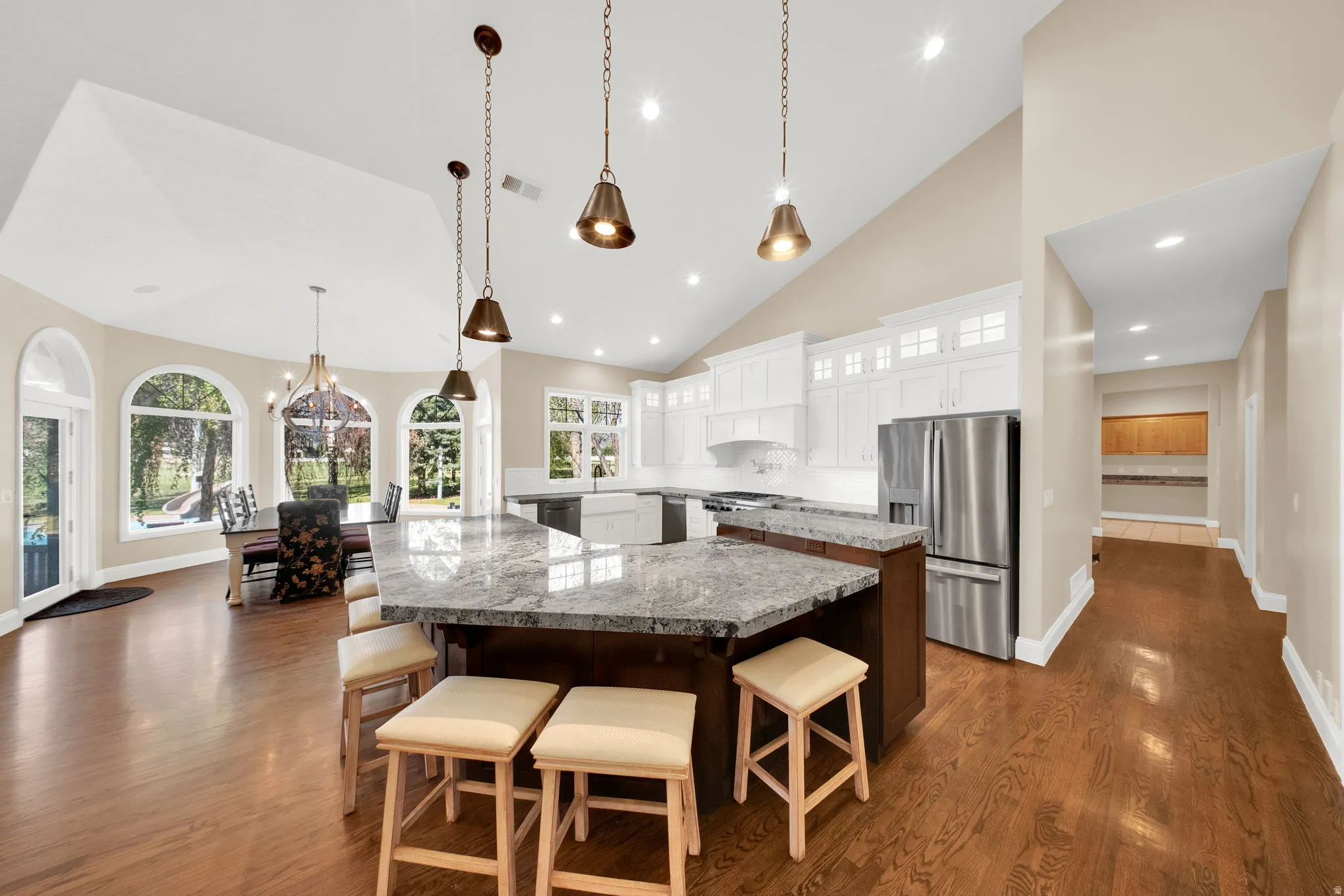 Spacious kitchen featuring a large island with seating, stainless steel appliances, white cabinetry, and recessed lighting