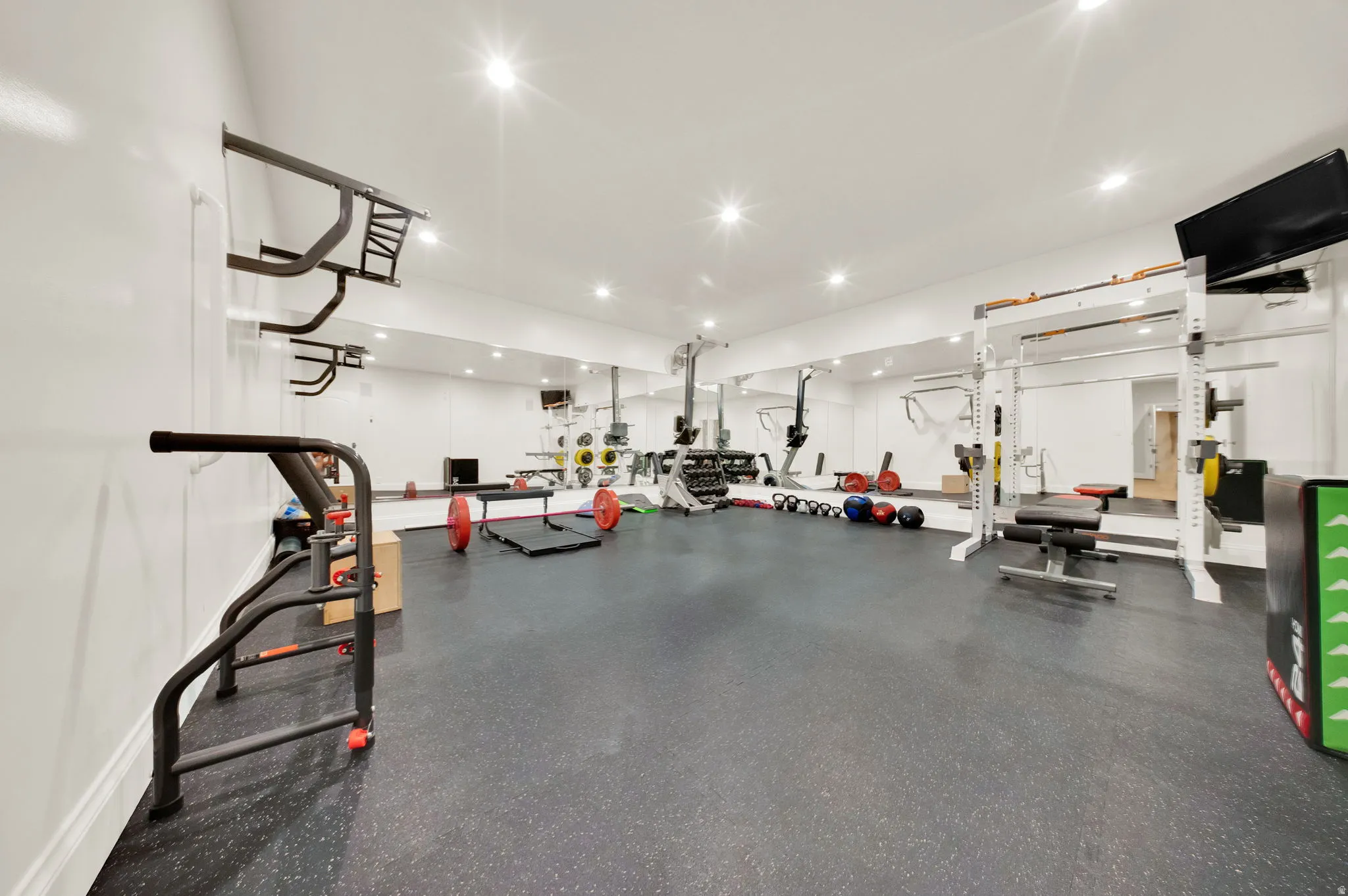 Dedicated fitness space with recessed lighting, full-wall mirrors, and resilient rubber flooring