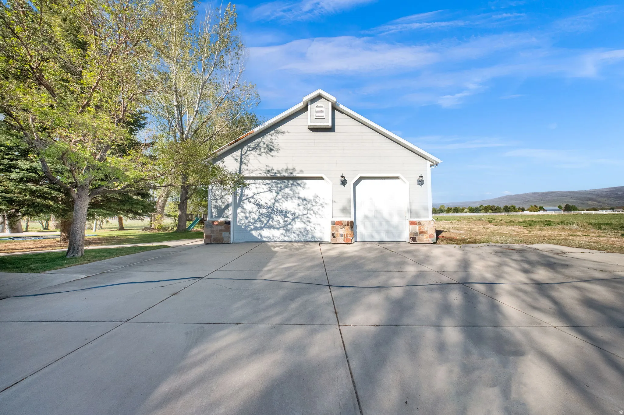 Two-car garage with light gray siding and stone veneer accents