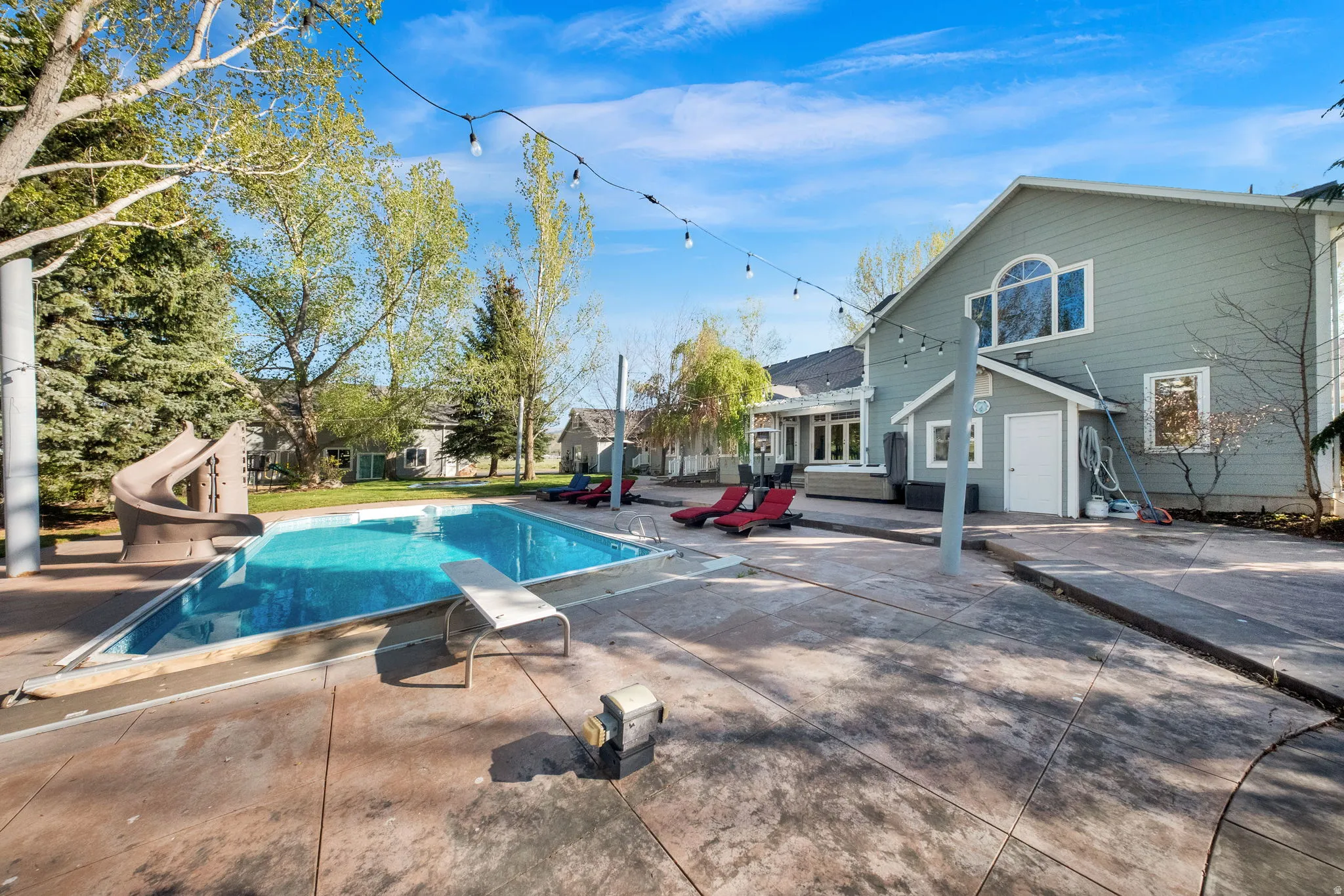 Expansive backyard featuring a rectangular swimming pool with an integrated slide and diving board