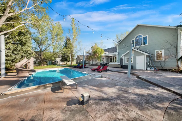Expansive backyard featuring a rectangular swimming pool with an integrated slide and diving board