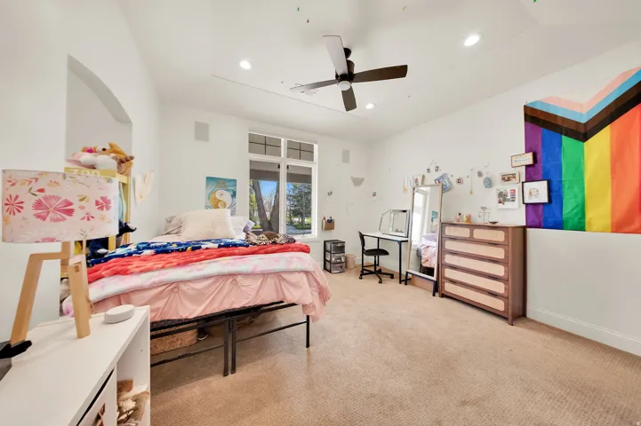 Carpeted room featuring a ceiling fan, recessed lighting, and a large window with multiple panes