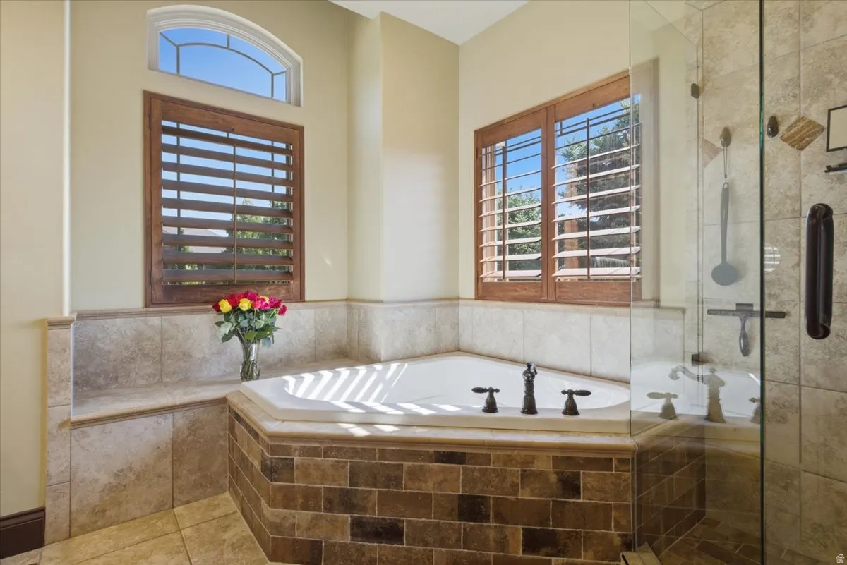 Corner soaking tub with bronze fixtures, surrounded by a tiled deck and wainscoting
