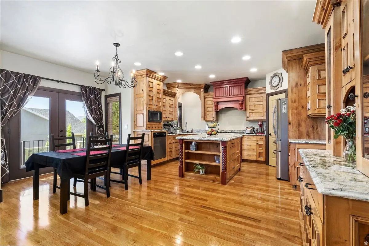 Open-concept kitchen and dining area featuring wood-finish flooring, recessed lighting, and a chandelier