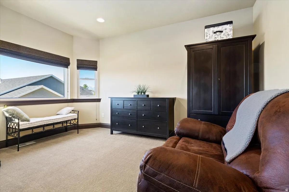 Carpeted room featuring a large horizontal window and an additional vertical window with dark wood trim, recessed lighting, and light-toned walls