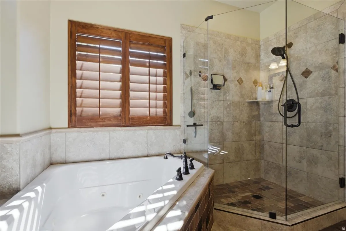 Corner jetted soaking tub with a tiled surround, complemented by a walk-in shower featuring a glass enclosure