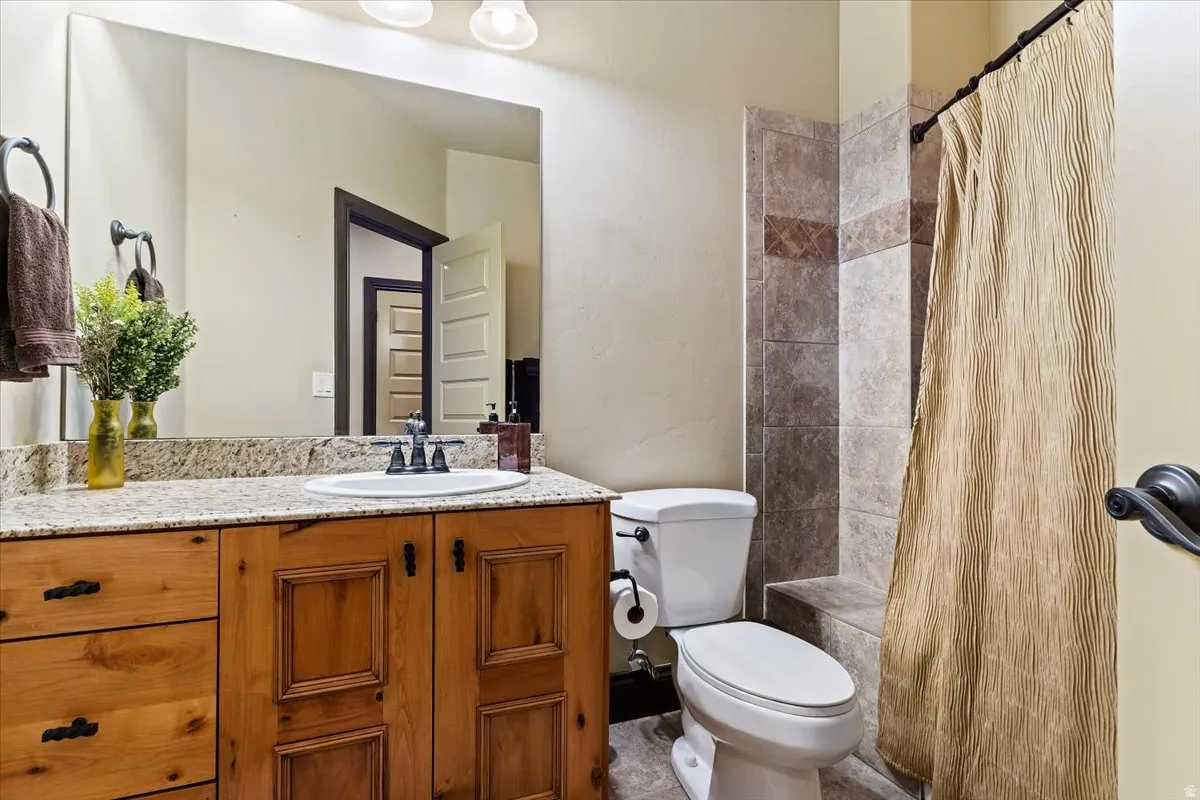 Bathroom featuring a wood vanity with granite-finish countertop, undermount sink, and dark bronze-finish fixtures