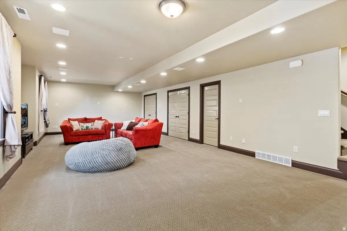 Spacious carpeted room featuring recessed lighting, a ceiling-mounted light fixture, and multiple panel doors with frosted glass inserts