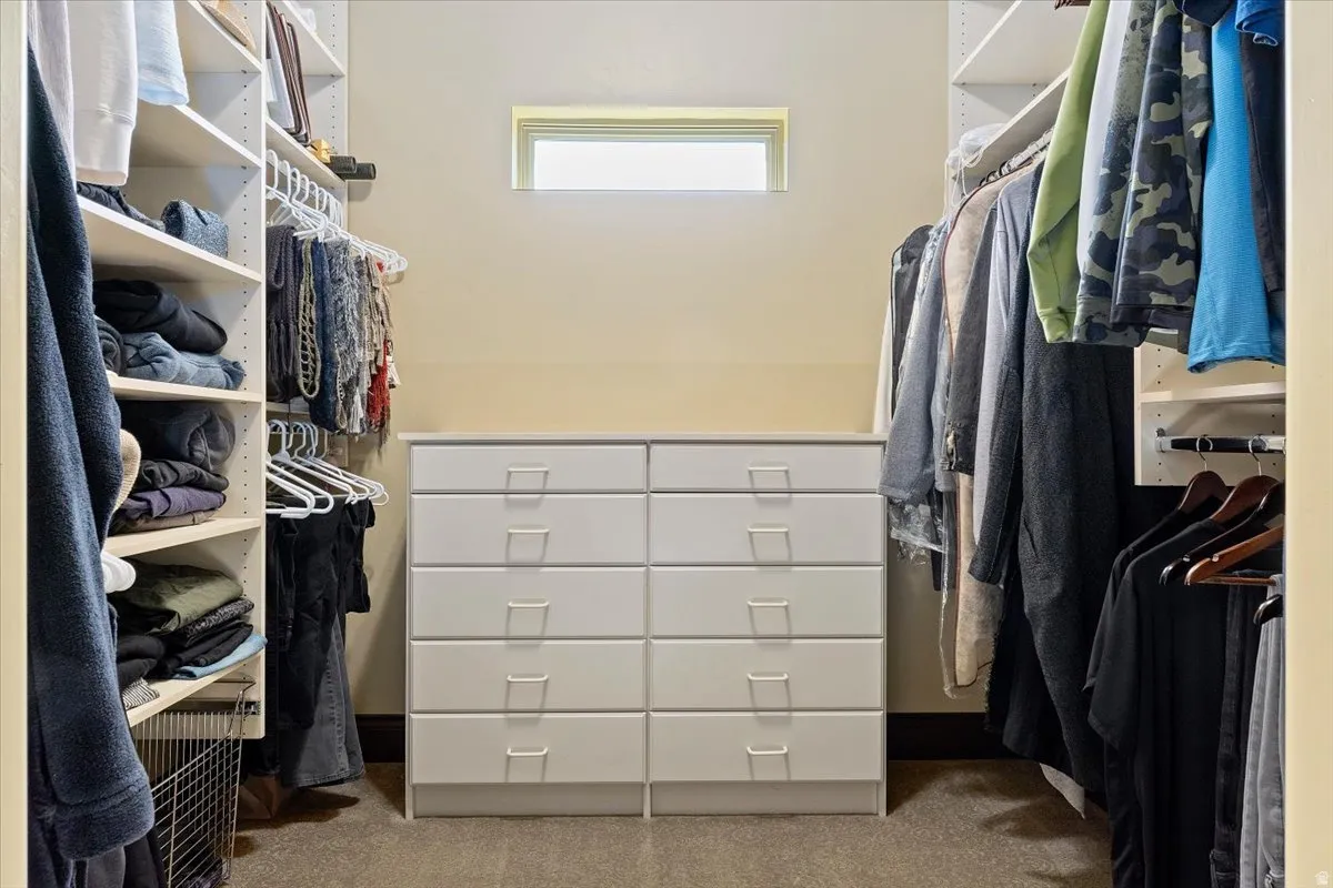 Walk-in closet featuring extensive built-in shelving, hanging rods, and a central white dresser with eight drawers