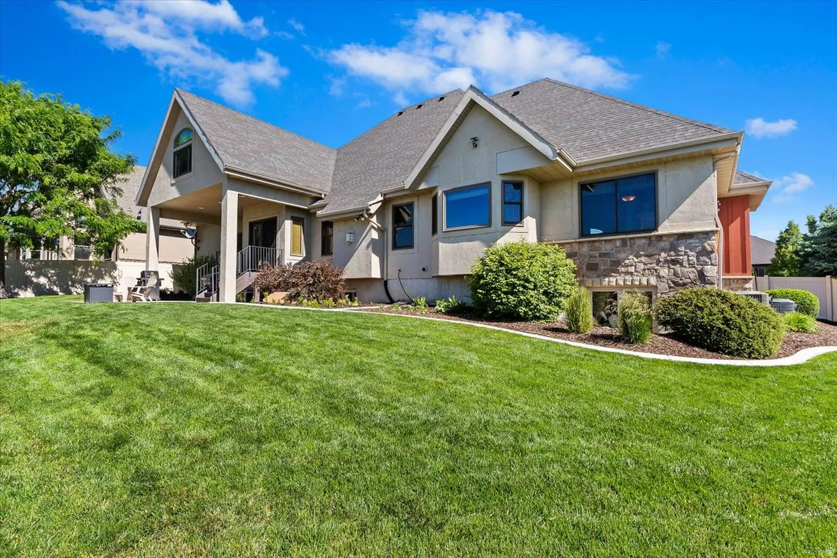 Expansive green lawn bordering the rear of a stucco and stone-clad residence
