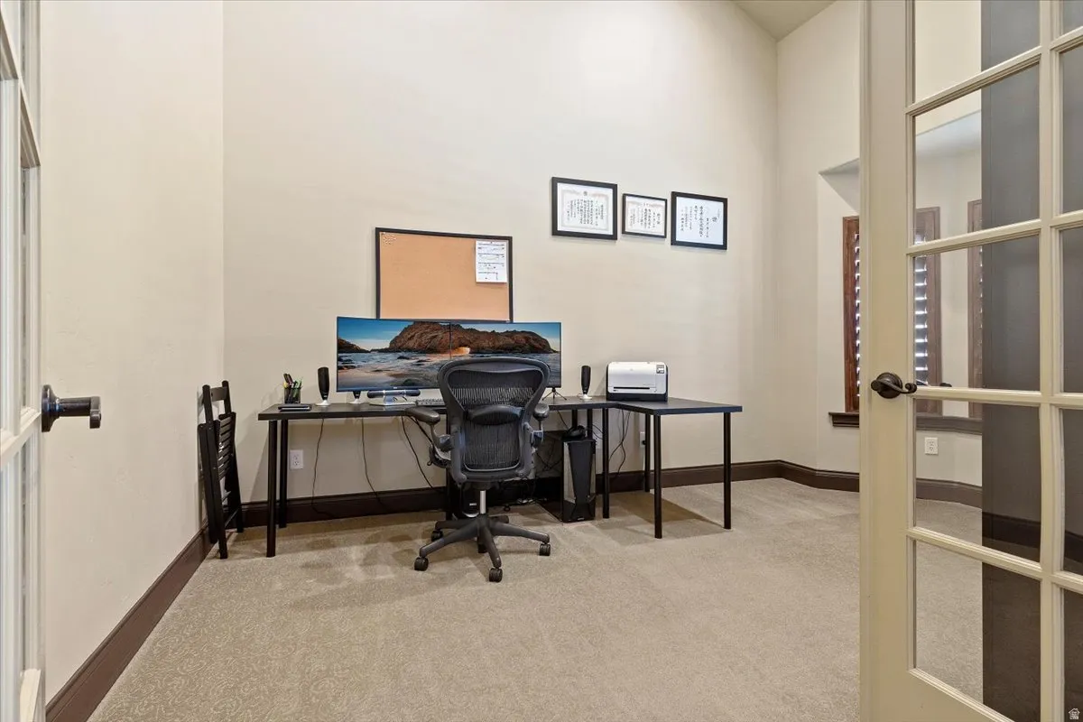 Carpeted room featuring tall ceilings, light-toned walls, and dark wood-finish baseboards