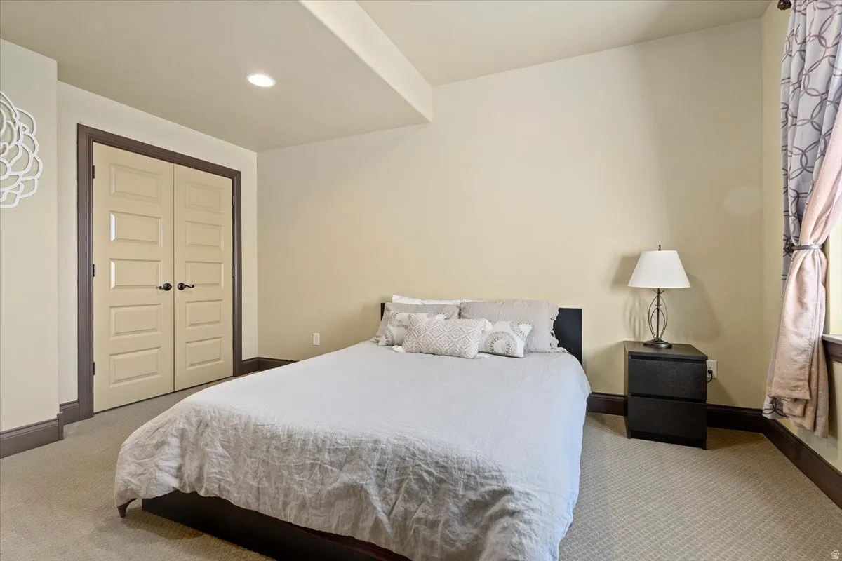 Carpeted bedroom with recessed lighting and a window featuring patterned drapes