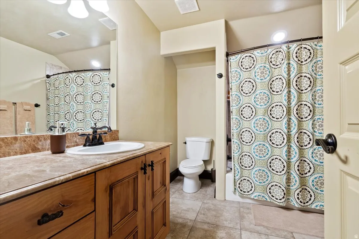Bathroom featuring a wood-finish vanity with a built-in sink, a stone-finish countertop, and a vanity mirror with overhead lighting