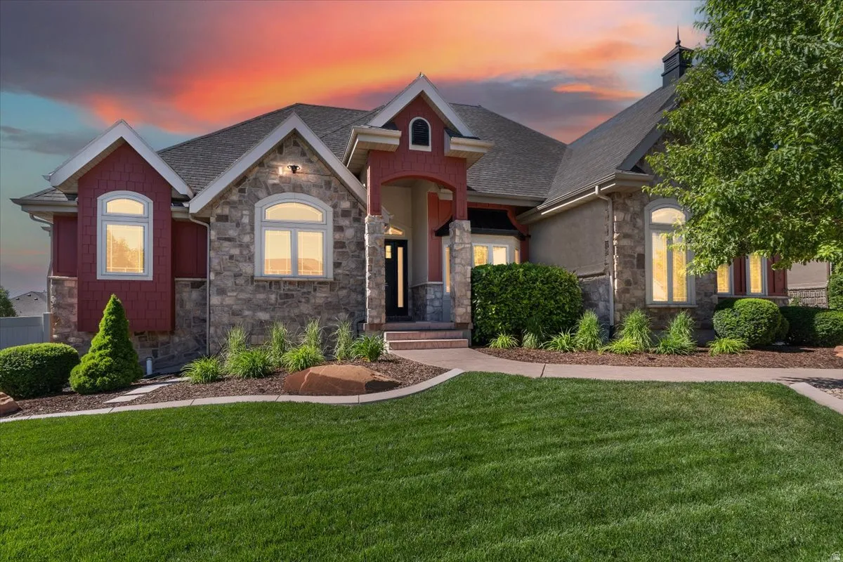 Stone and shingle exterior featuring architectural gables, arched windows, an inviting entryway, and a well-maintained lawn