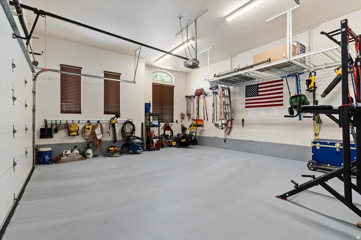 Spacious garage with light gray flooring, white walls, and a white garage door