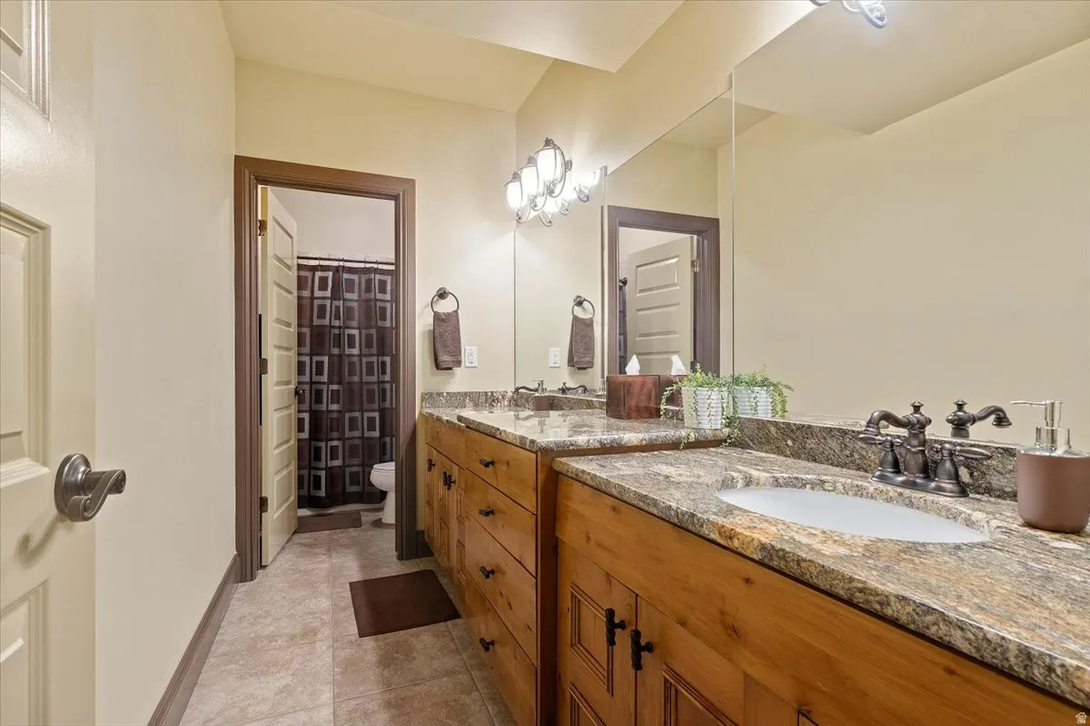 Double vanity featuring wood cabinetry, granite countertops, and undermount sinks