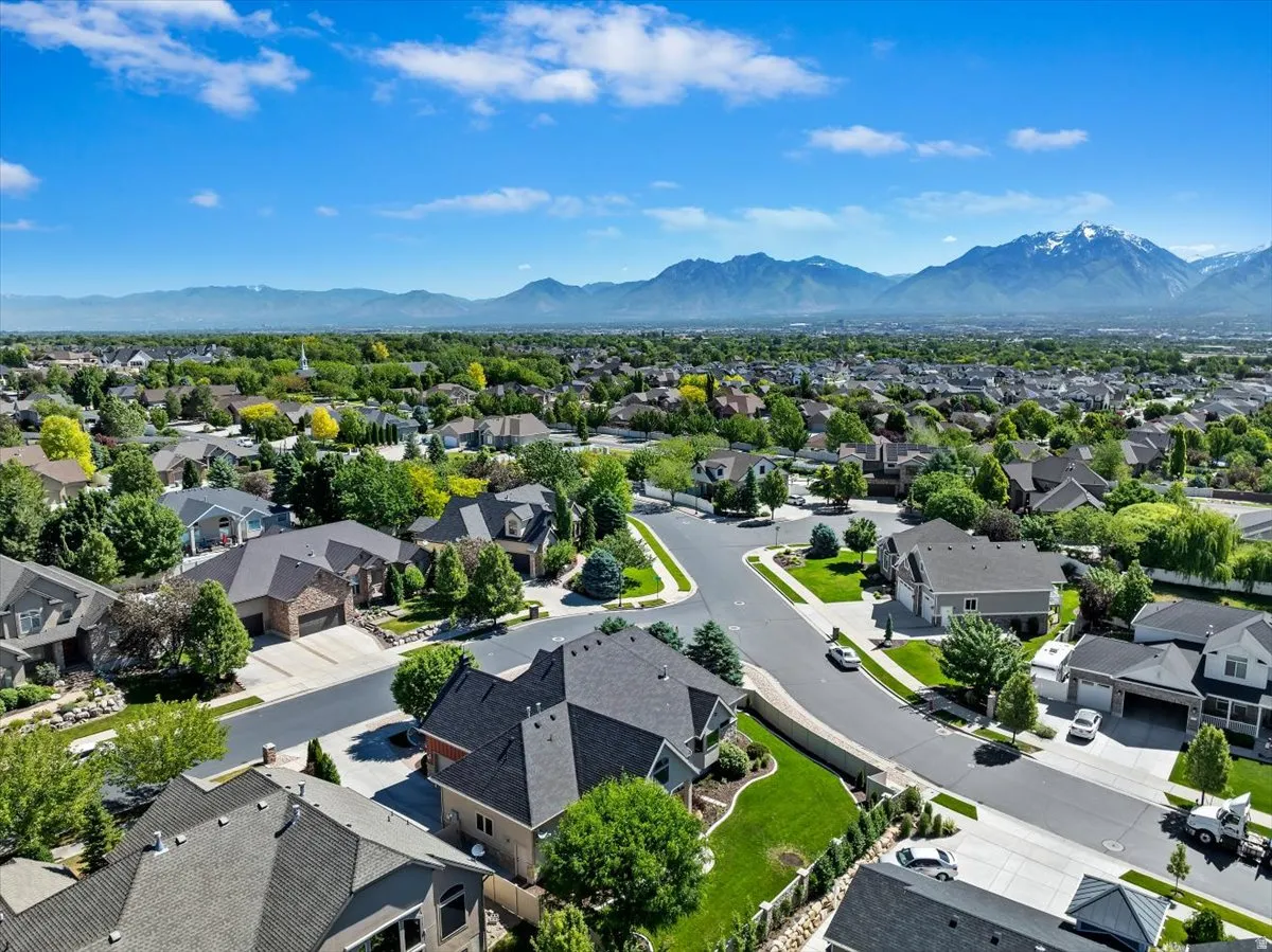 Expansive residential area featuring numerous single-family homes, mature trees, and a clear mountain range backdrop
