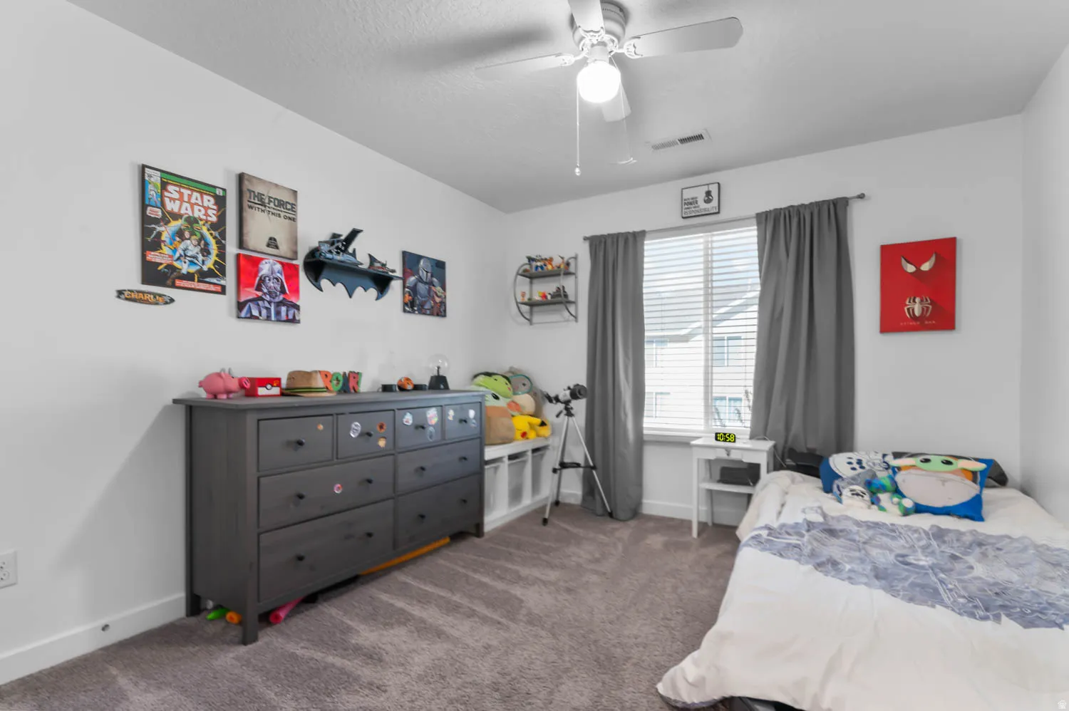 Carpeted room featuring a white ceiling fan with integrated lighting, a large window with blinds and dark-toned drapes, and white baseboards