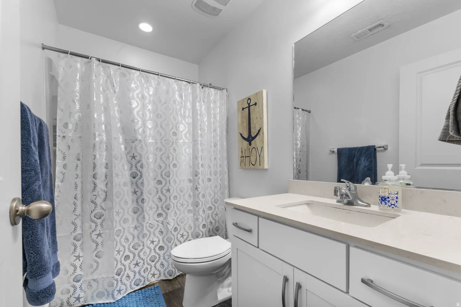 Bathroom featuring a built-in vanity with a single sink, light-toned countertop, and white cabinetry with brushed nickel hardware
