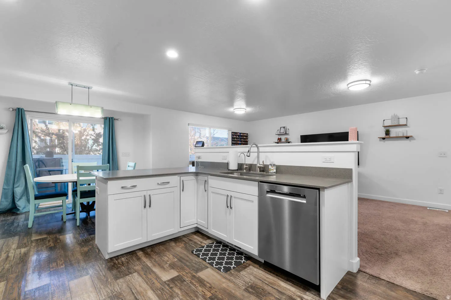 Contemporary kitchen featuring white cabinetry, a stainless steel dishwasher, a single basin sink with a high-arc faucet, and light gray countertops