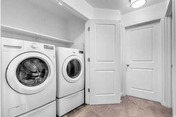 Dedicated laundry area featuring a front-loading washer and dryer, integrated pedestals, and convenient shelving