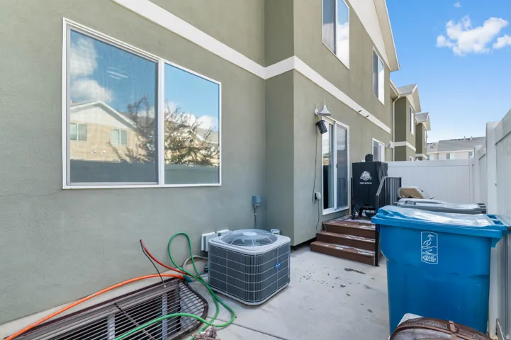 Rear exterior patio featuring a stucco finish, multi-pane windows, white trim, and a white privacy fence