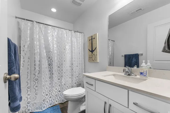 Bathroom featuring a built-in vanity with a single sink, light-toned countertop, and white cabinetry with brushed nickel hardware