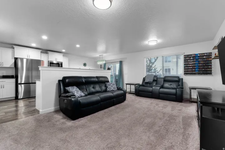 Open-concept living area featuring a neutral carpeted floor and recessed lighting