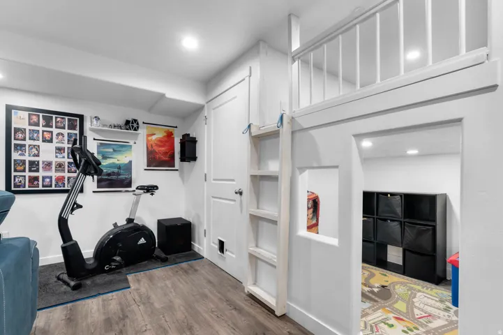 White-painted built-in loft structure with a ladder and railing, featuring an archway opening