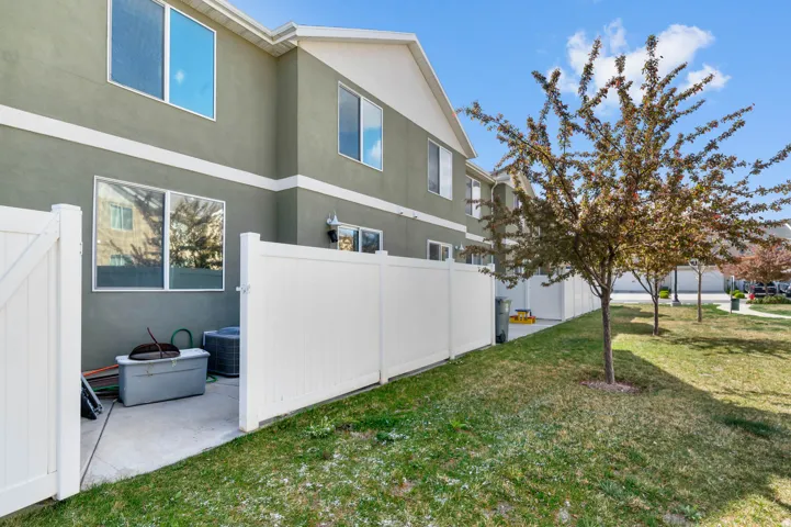Green exterior facade with white trim, featuring multiple windows and a private patio space