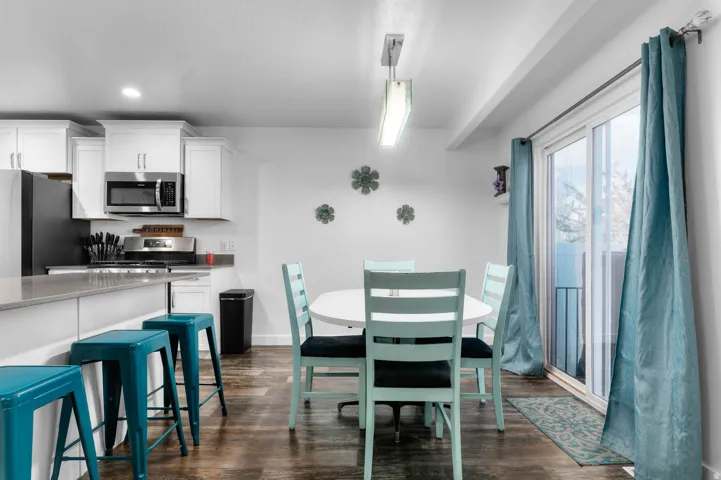 Kitchen and dining area featuring wood-finish flooring, white cabinetry, and stainless steel appliances