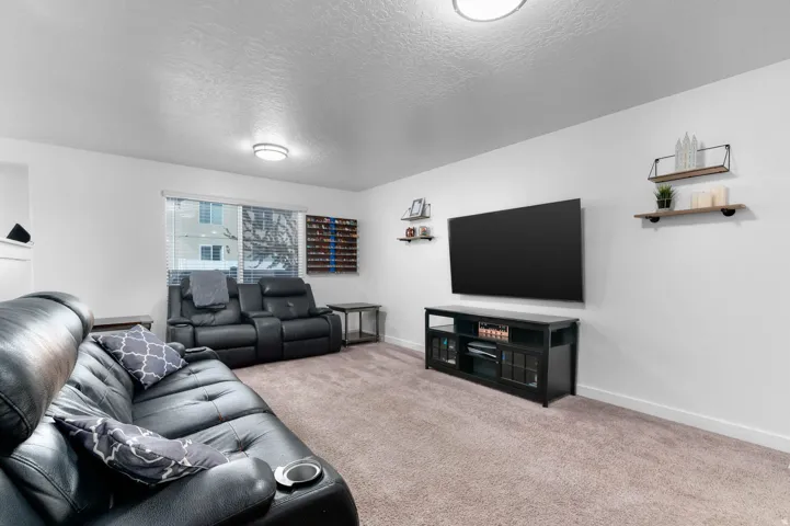 Carpeted living area featuring white walls and a window with blinds