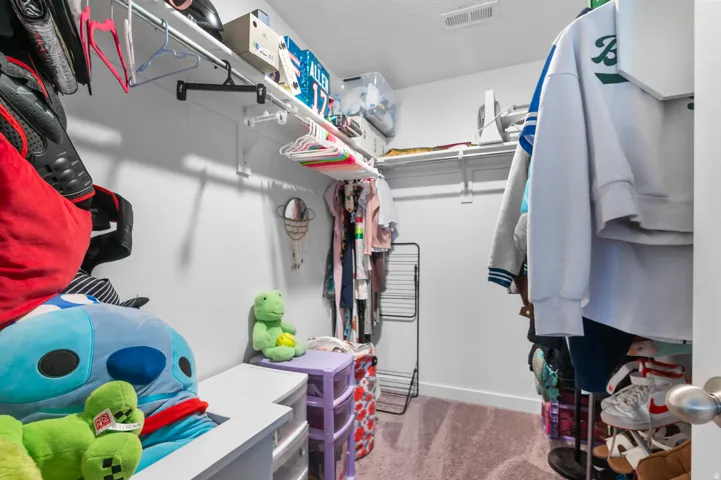 Spacious walk-in closet featuring white wire shelving and hanging rods