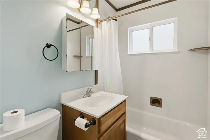 Bathroom featuring a single vanity with a white countertop and wood-finish cabinetry, a mirrored medicine cabinet, and a window above the bathtub